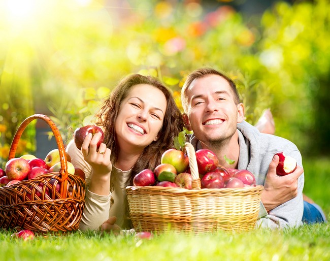 Happy People Eating Organic Apples in Autumn Garden.Healthy Food