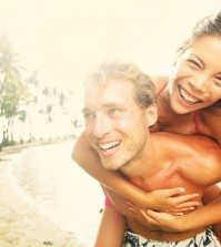 Happy young joyful couple having beach fun piggybacking laughing