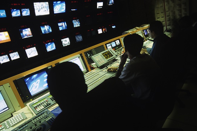 Rear view of operators in central control room at television station