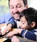 Father and son playing guitar at home