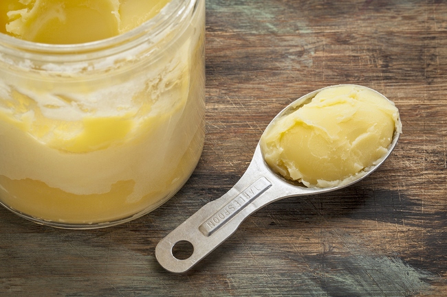jar and measuring tablespoon of ghee - clarified butter on grung