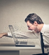 furious businessman throws a punch into the computer