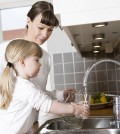 Small Girl in the kitchen with her mother drinking water