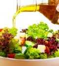 Fresh salad with olive oil isolated on white background, pouring