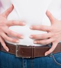 Close-up of female with bloated belly as flatulence concept isolated on white background