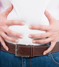 Close-up of female with bloated belly as flatulence concept isolated on white background