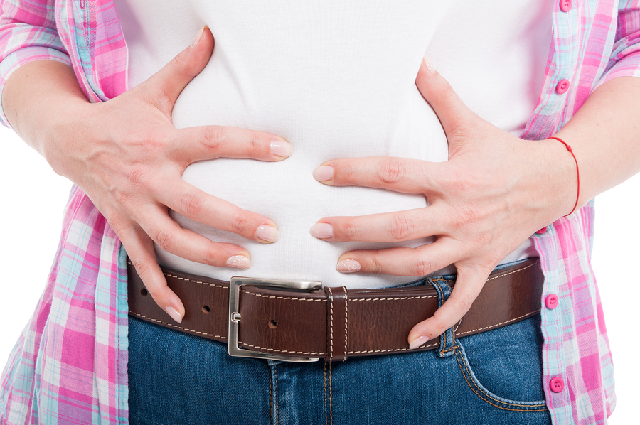 Close-up of female with bloated belly as flatulence concept isolated on white background