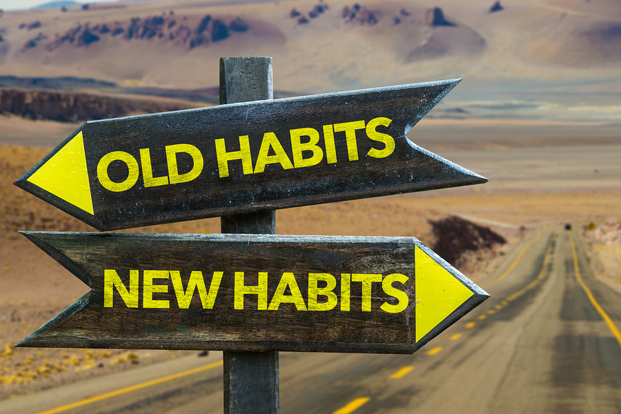 Old Habits - New Habits signpost in a desert road background